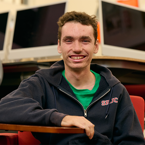 Noah McSweeney, SRJC autistic student, smiles at the camera while sitting in the newsroom at Santa Rosa Junior Colege