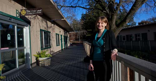 Woman standing at railing, in front of the Oak Leaf office