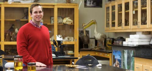 Man in red sweater standing in a college biology lab