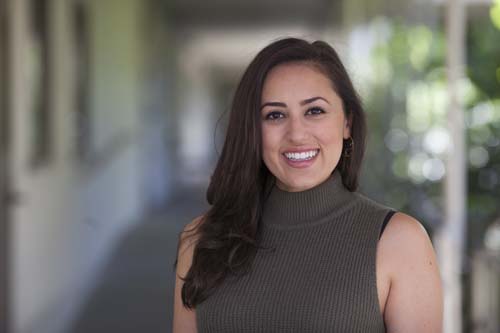 Smiling woman in sleeveless top standing in a breezeway