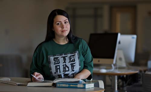 Woman seated at a desk, looking up from reading a book