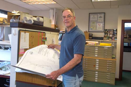 Man standing in a planning office, holding blueprints