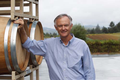 Smiling man leaning against outdoor barrel rack