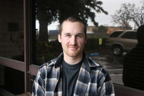 Man in a flannel shirt standing in front of a reflective glass wall