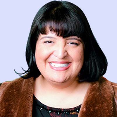 Smiling Latina woman in furry brown jacket against lilac background