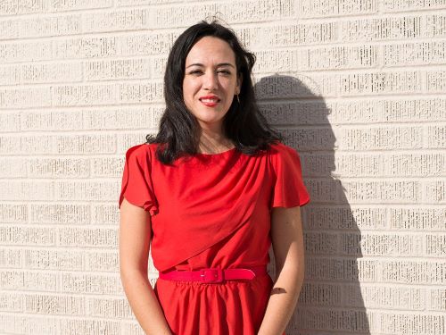 Woman in red dress standing before white brick wall