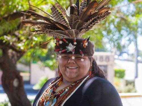Head and shoulder portrait of smiling woman in California native tribal regalia