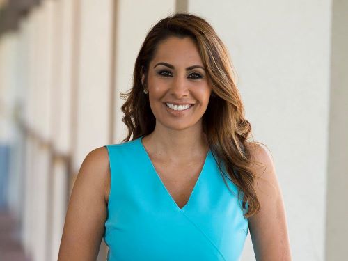 Smiling woman in blue, standing in a breezeway