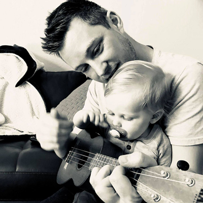 SRJC alumnus Tim O'Connell playing guitar for one of his toddlers